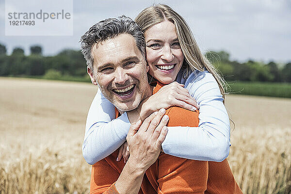Glückliche Frau umarmt Mann vor dem Feld