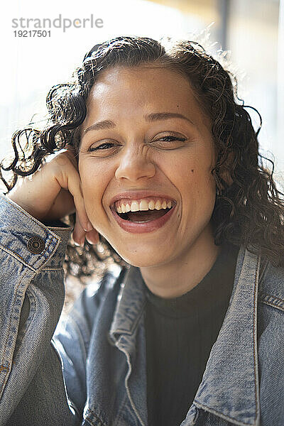 Glückliche junge Frau  die an einem sonnigen Tag lacht