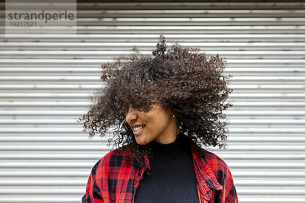Smiling woman tossing hair in front of shutter