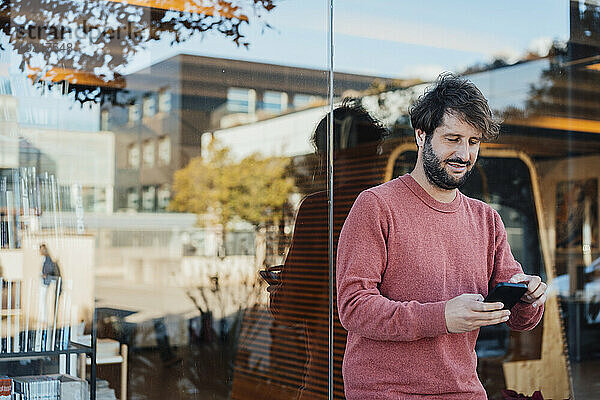 Mann benutzt Smartphone in der Nähe einer Glaswand