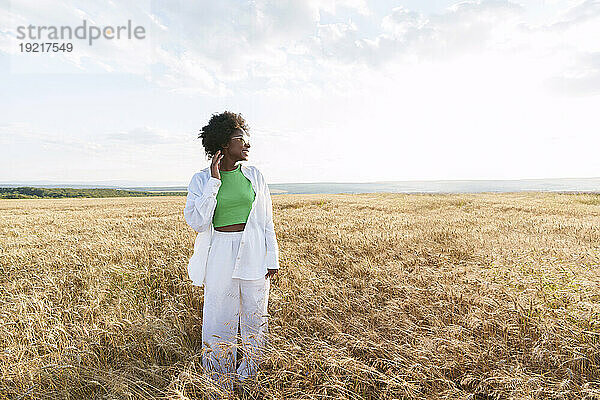 Junge Frau in weißer und grüner Freizeitkleidung steht auf dem Feld