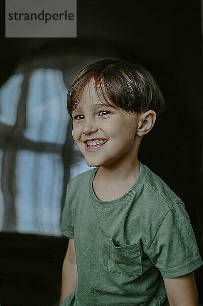 Lächelnder Junge im grünen Hemd zu Hause