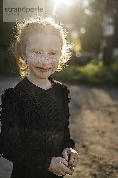 Lächelndes rothaariges Mädchen steht im Park