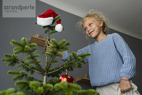 Lächelndes Mädchen  das zu Hause den Weihnachtsbaum schmückt