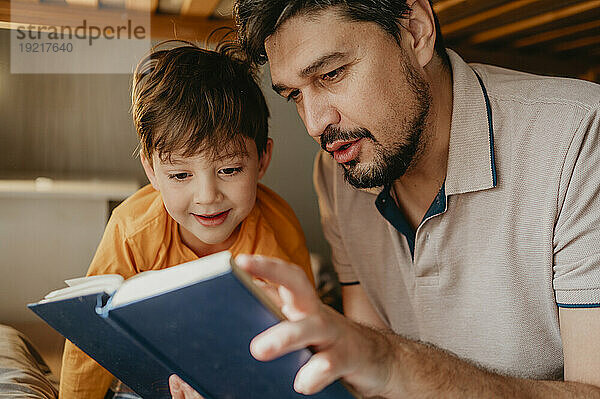 Vater liest seinem Sohn im Schlafzimmer zu Hause ein Buch vor