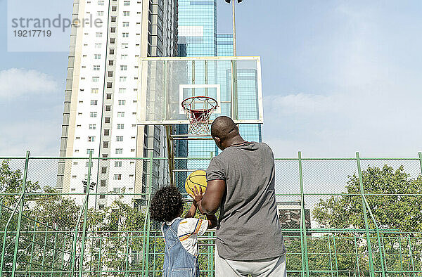 Vater und Sohn spielen an einem sonnigen Tag Basketball