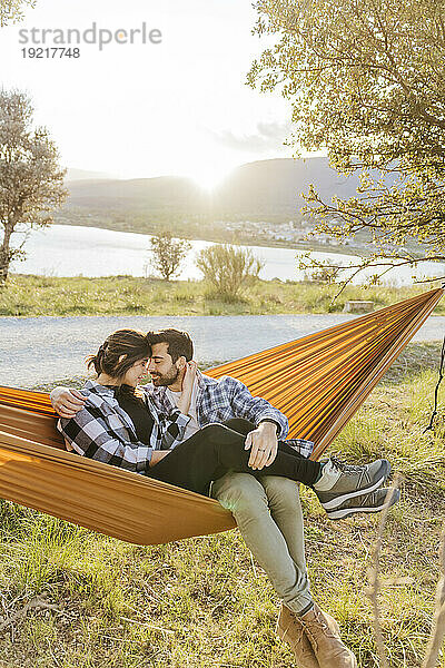 Boyfriend and girlfriend spending leisure time sitting in hammock