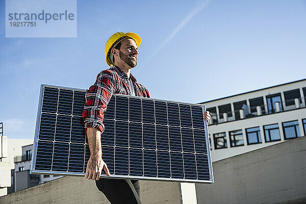 Lächelnder Ingenieur mit Schutzhelm und Solarpanel