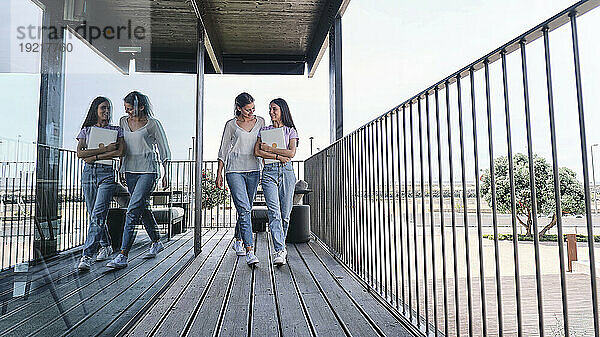 Zwei junge Frauen gehen nebeneinander auf dem Balkon