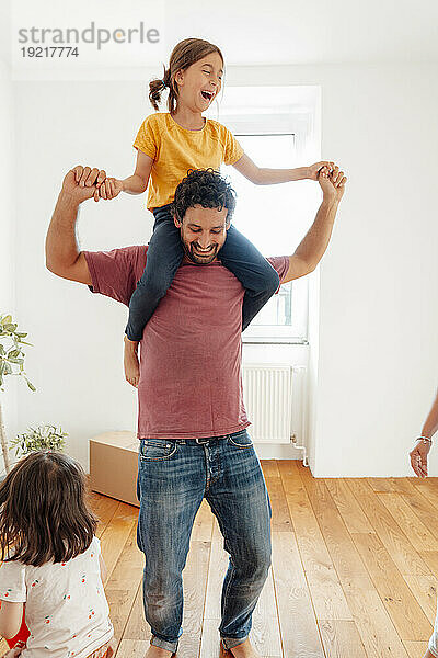 Glücklicher Vater trägt seine Tochter zu Hause auf den Schultern