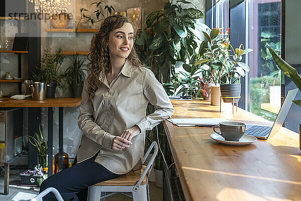 Lächelnde Geschäftsfrau sitzt am Tisch im Café