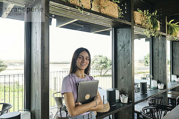 Portrait of beautiful brunette woman standing in cafe with laptop in hands