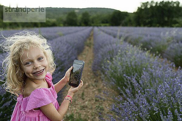 Glückliches Mädchen mit Smartphone im Lavendelfeld