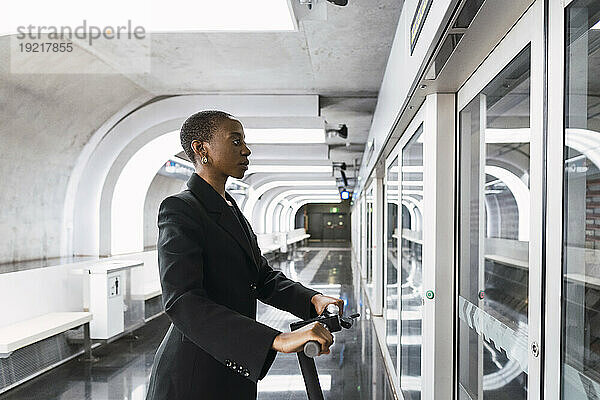 Pendler mit Elektroroller blickt auf den U-Bahn-Fahrplan