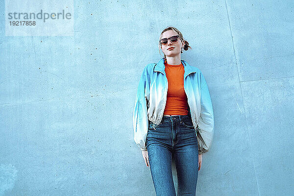 Frau mit Sonnenbrille steht vor blauer Wand