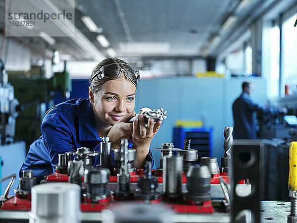Lächelnder Auszubildender lernt  CNC-Werkzeug in der Fabrik zu steuern