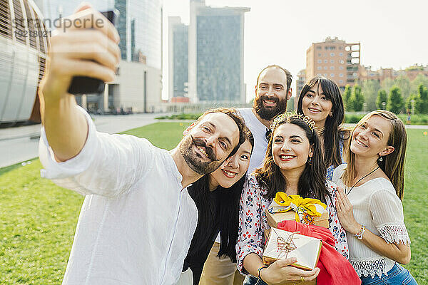 Glückliche Freunde machen Selfie und feiern gemeinsam Geburtstag im Park