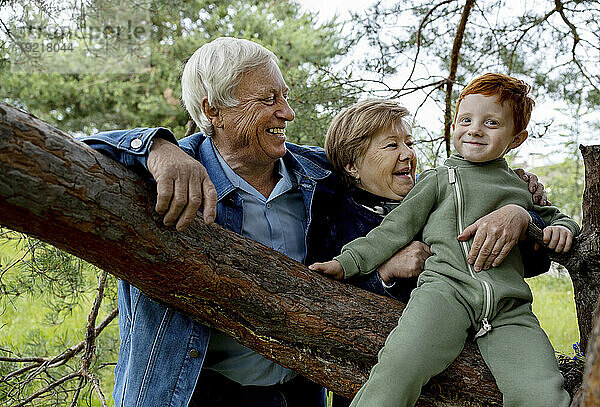 Glückliches Seniorenpaar spielt mit Enkel im Wald
