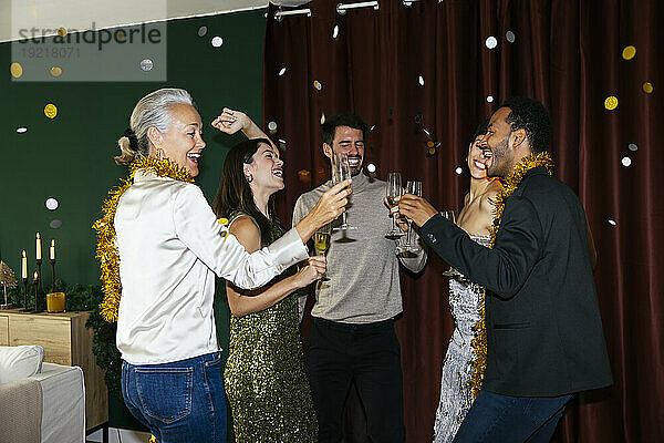 Fröhliche Männer und Frauen mit Trinkgläsern tanzen auf der Neujahrsparty