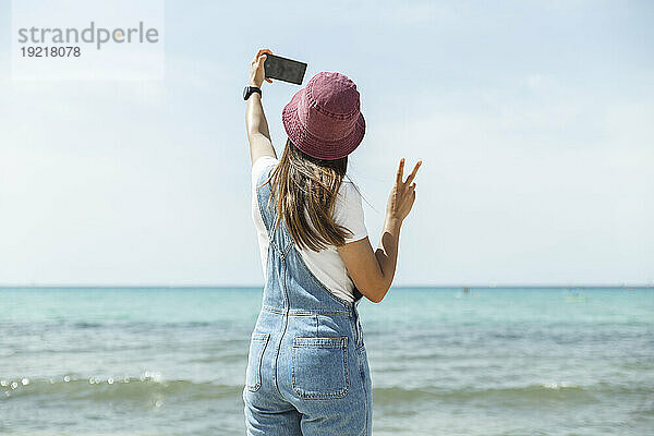 Frau macht Selfie am Meer unter dem Himmel