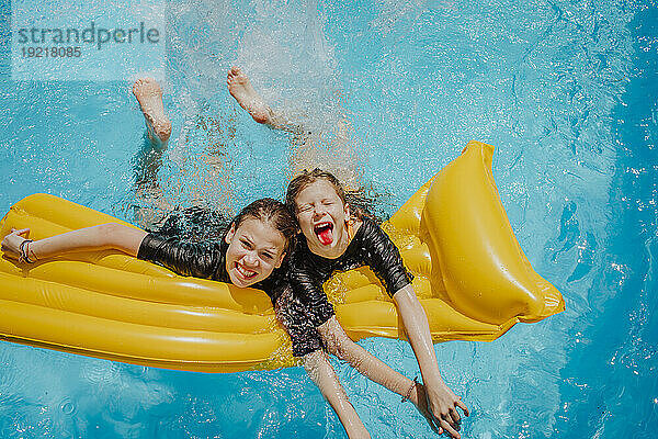 Happy friends having fun and leaning on pool raft at sunny day