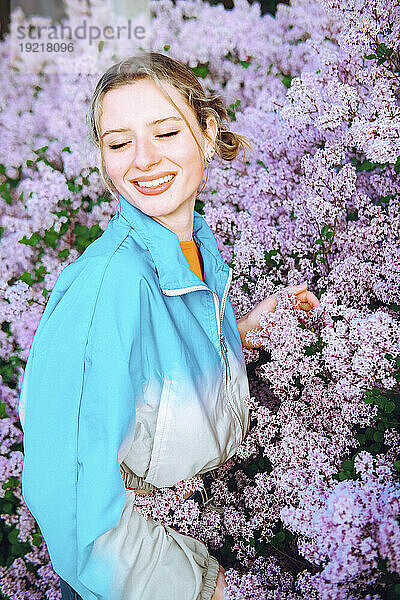 Happy woman with eyes closed standing amidst flowers