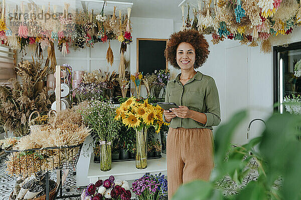 Lächelnder Florist hält Tablet-PC im Blumenladen