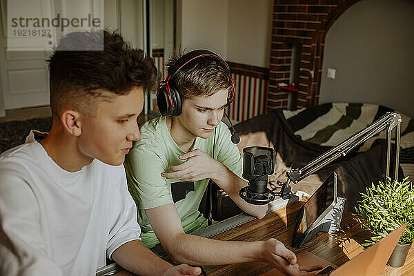 Teenage friends podcasting in front of tablet PC and laptop at home