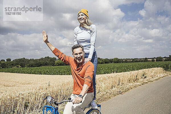 Glücklicher reifer Mann  der Frau auf der Straße eine Fahrradtour gibt