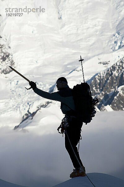 Bergsteiger-Silhouette auf dem Gipfel des Kontrollturms mit Gletschereisfall und Gletscherspalten am Mount Foraker im Hintergrund  Kahiltna-Gletscher  Alaska Range  Inneres Alaskas  Sommer