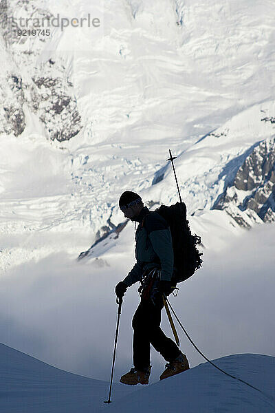 Bergsteiger-Silhouette auf dem Gipfel des Kontrollturms mit Gletschereisfall und Gletscherspalten am Mount Foraker im Hintergrund  Kahiltna-Gletscher  Alaska Range  Inneres Alaskas  Sommer