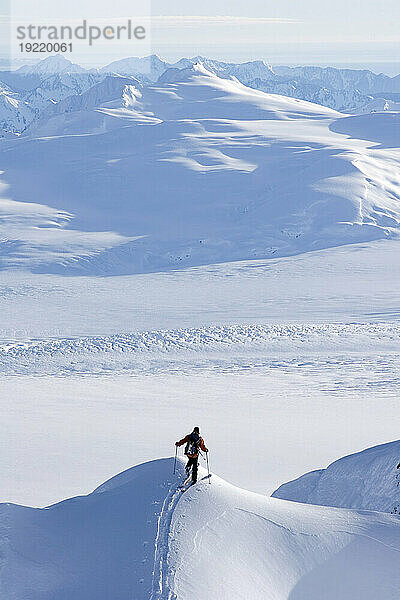 Skifahrer klettert den Grat über dem Sargent Icefield im Süden Alaskas hinauf
