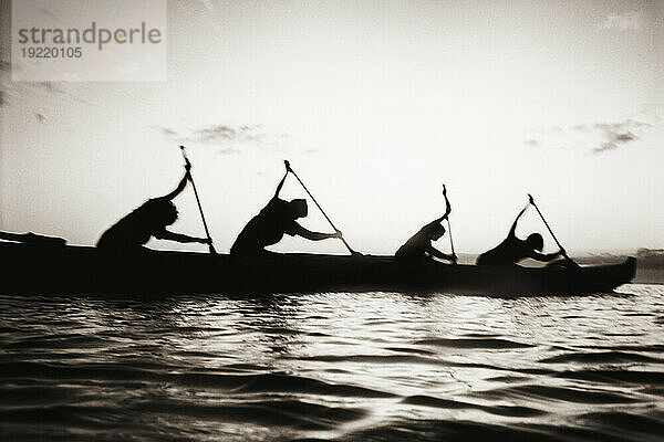 Hawaii  Kanurennen von Molokai nach Oahu  Silhouetten der Paddler bei Sonnenuntergang (Schwarz-Weiß-Foto).