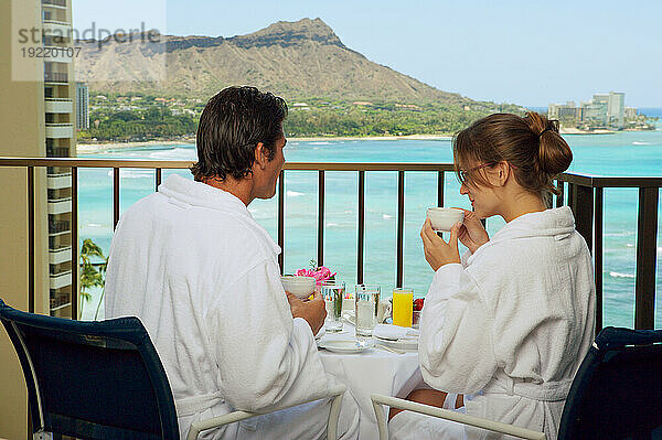 Hawaii  Oahu  Waikiki  Paar genießt Frühstück auf ihrem Hotel Lanai  Diamond Head Hintergrund.