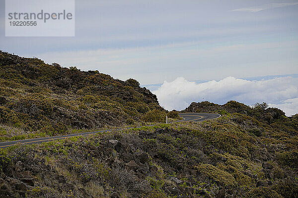 Malerischer Blick auf eine scharfe Kurve auf der Bergstraße mit Blick auf die Wolken über dem Berghang auf der Straße von Haleakala hinunter; Maui  Hawaii  Vereinigte Staaten von Amerika