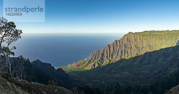 Malerische Aussicht auf die grün bedeckten Bergklippen der Napali-Küste entlang des Kalalau Trail auf der hawaiianischen Insel Kauai vor dem ruhigen blauen Wasser des Pazifischen Ozeans; Kauai  Hawaii  Vereinigte Staaten von Amerika