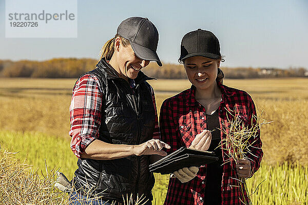 Eine Bäuerin steht auf den Feldern und bringt ihrem Lehrling moderne Anbautechniken für Rapsanbau unter Einsatz von drahtlosen Technologien und landwirtschaftlicher Software bei. Alcomdale  Alberta  Kanada