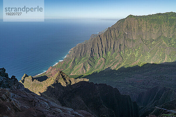 Malerische Aussicht auf die grün bedeckten Bergklippen der Napali-Küste entlang des Kalalau Trail auf der hawaiianischen Insel Kauai vor dem ruhigen blauen Wasser des Pazifischen Ozeans; Kauai  Hawaii  Vereinigte Staaten von Amerika