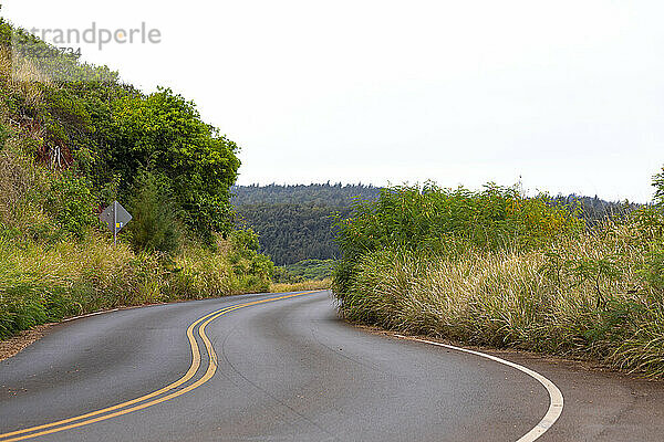 Malerische Aussicht auf die kurvenreiche West Maui Road durch die grünen Hügel an einem bewölkten Tag in West Maui; Maui  Hawaii  Vereinigte Staaten von Amerika