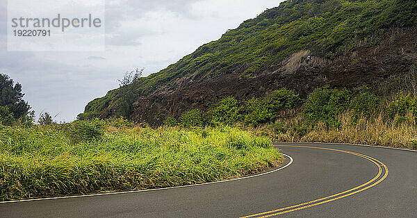 Nahaufnahme einer Kurve auf der Straße und bewölktem Himmel durch die grünen Hügel entlang einer malerischen Fahrt in West Maui; Maui  Hawaii  Vereinigte Staaten von Amerika