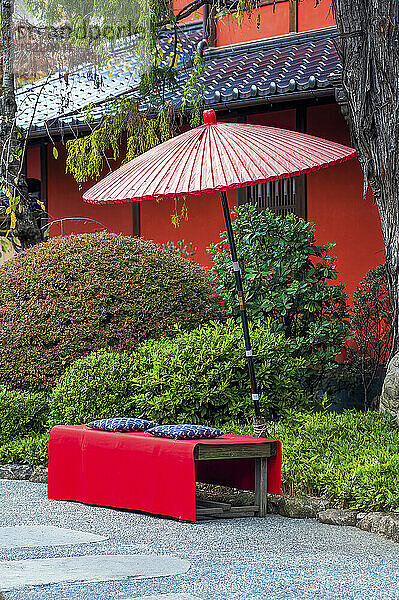 Roter Regenschirm über einer Bank vor einem Tempel; Tokyo  Japan