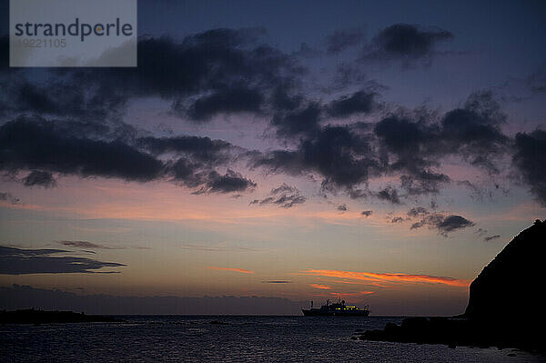 Silhouette eines Kreuzfahrtschiffes bei Sonnenuntergang in der Nähe der Insel San Cristobal im Galapagos-Inseln-Nationalpark; Insel San Cristobal  Galapagos-Inseln  Ecuador