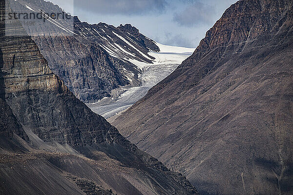 Blick durch die Berglandschaft auf eine eisige Gletschermasse im Kong Oscar Fjord in Grönland; Ostgrönland  Grönland