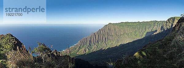 Malerische Aussicht auf die grün bedeckten Bergklippen der Napali-Küste entlang des Kalalau Trail auf der hawaiianischen Insel Kauai  vor einem strahlend blauen Himmel und dem ruhigen Wasser des Pazifischen Ozeans; Kauai  Hawaii  Vereinigte Staaten von Amerika