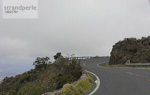 Kurvenreiche Bergstraße mit grauem  bewölktem Himmel entlang der malerischen Fahrt von Kihei nach Haleakala und zurück; Maui  Hawaii  Vereinigte Staaten von Amerika