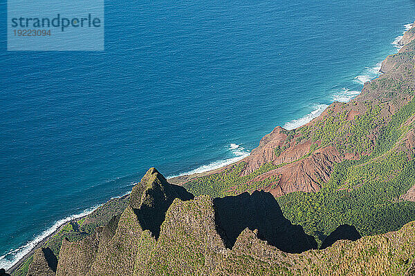 Malerische Aussicht von den grün bedeckten Bergklippen der Napali-Küste entlang des Kalalau Trail auf der hawaiianischen Insel Kauai mit dem ruhigen  blauen Wasser des Pazifischen Ozeans  das die Küste umspült; Kauai  Hawaii  Vereinigte Staaten von Amerika