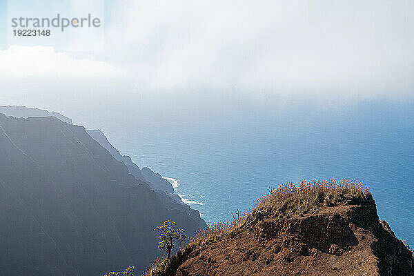 Ausblick von der Klippe mit malerischem Blick auf die Bergklippen der Napali-Küste entlang des Kalalau Trail auf der hawaiianischen Insel Kauai mit Blick auf die nebligen Wolken über dem blauen Wasser des Pazifischen Ozeans; Kauai  Hawaii  Vereinigte Staaten von Amerika