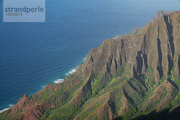 Malerische Nahaufnahme von den grün bedeckten Bergklippen der Napali-Küste entlang des Kalalau Trail auf der hawaiianischen Insel Kauai vor dem ruhigen  blauen Wasser des Pazifischen Ozeans; Kauai  Hawaii  Vereinigte Staaten von Amerika