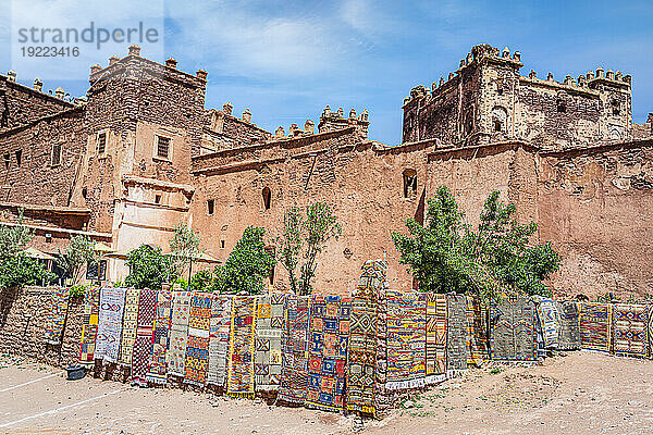 Bunte handgefertigte Teppiche zum Verkauf hängen vor den alten Ruinen der Telouet Kasbah  Hoher Atlas  Marokko  Nordafrika  Afrika