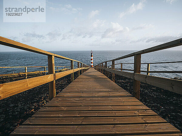 Leuchtturm Farolim dos Fenais da Ajuda mit einem symmetrischen Holzweg  der dorthin führt  Insel Sao Miguel  Azoren  Portugal  Atlantik  Europa